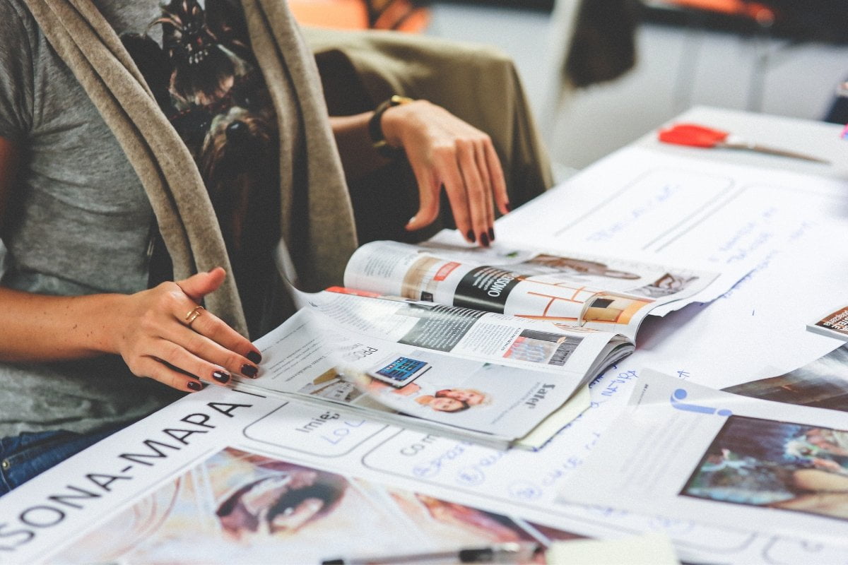 A group of people sitting around a table discussing PR and marketing strategies while flipping through magazines.