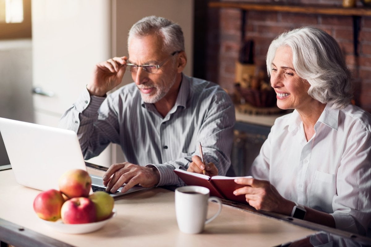 An older couple working on a laptop at home, ditching Internet Explorer for a smoother browsing experience.