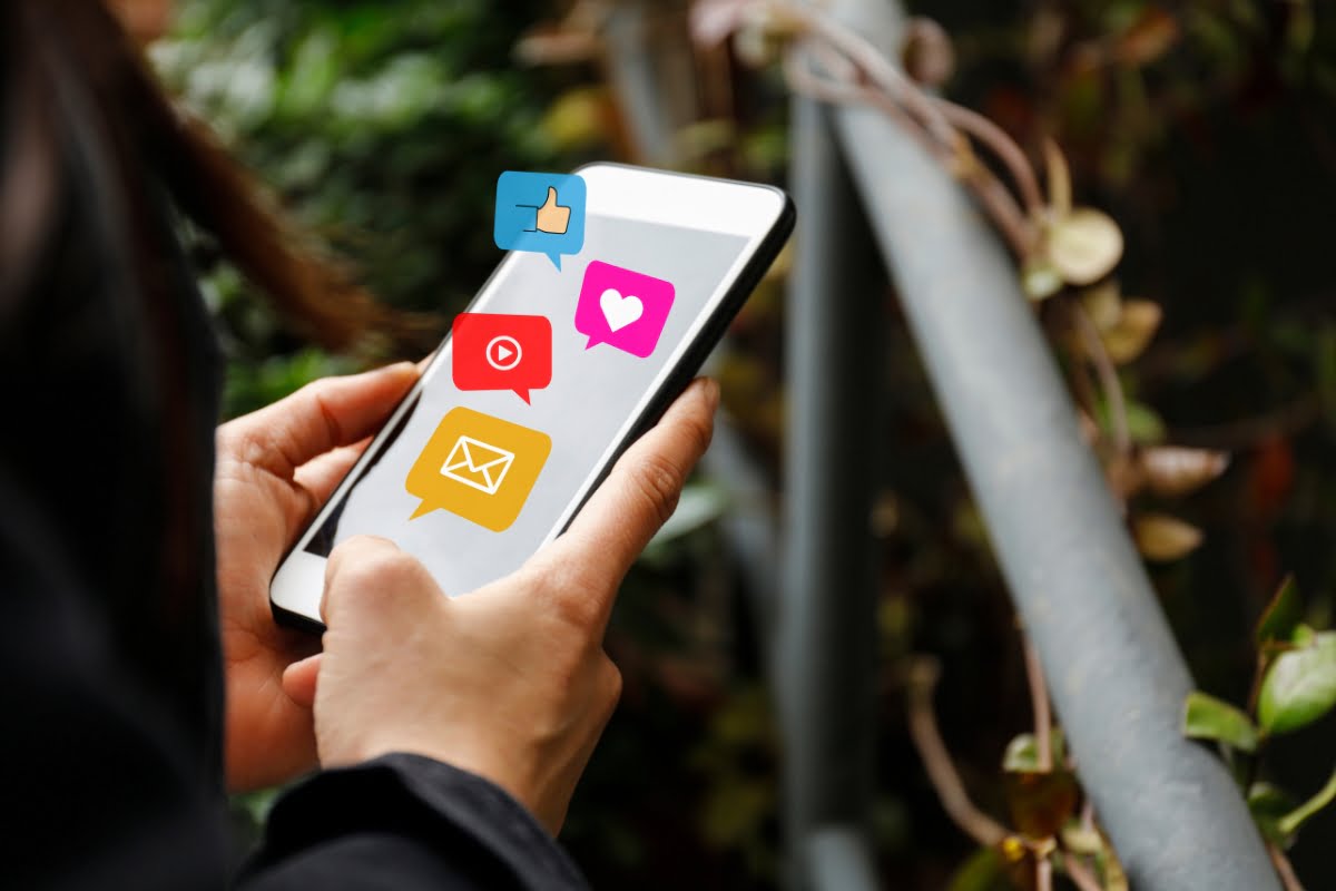 A woman holding a smart phone with social icons and link shorteners on it.