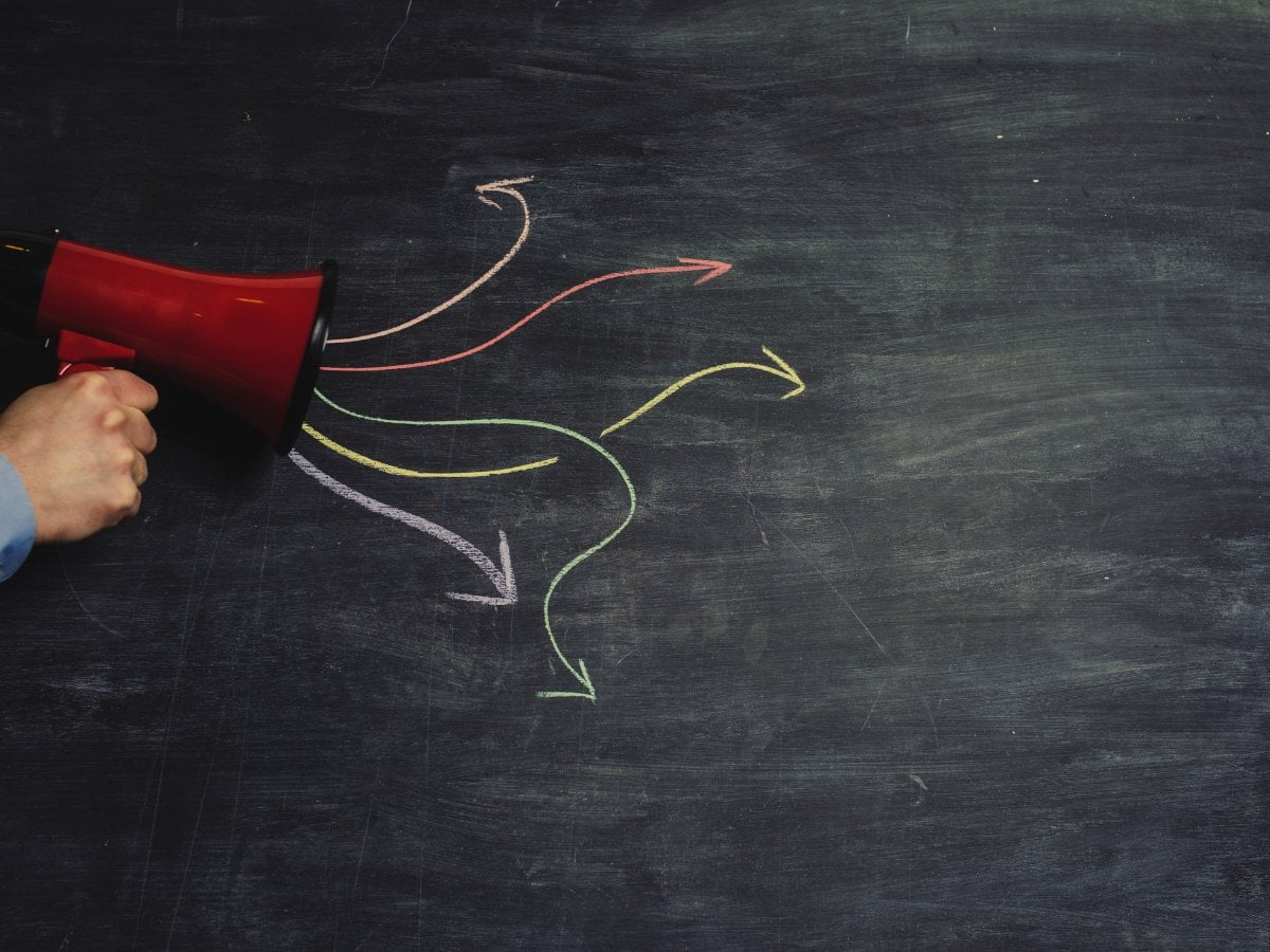 A man utilizing word of mouth marketing techniques with a megaphone in front of a chalkboard annotated with arrows.