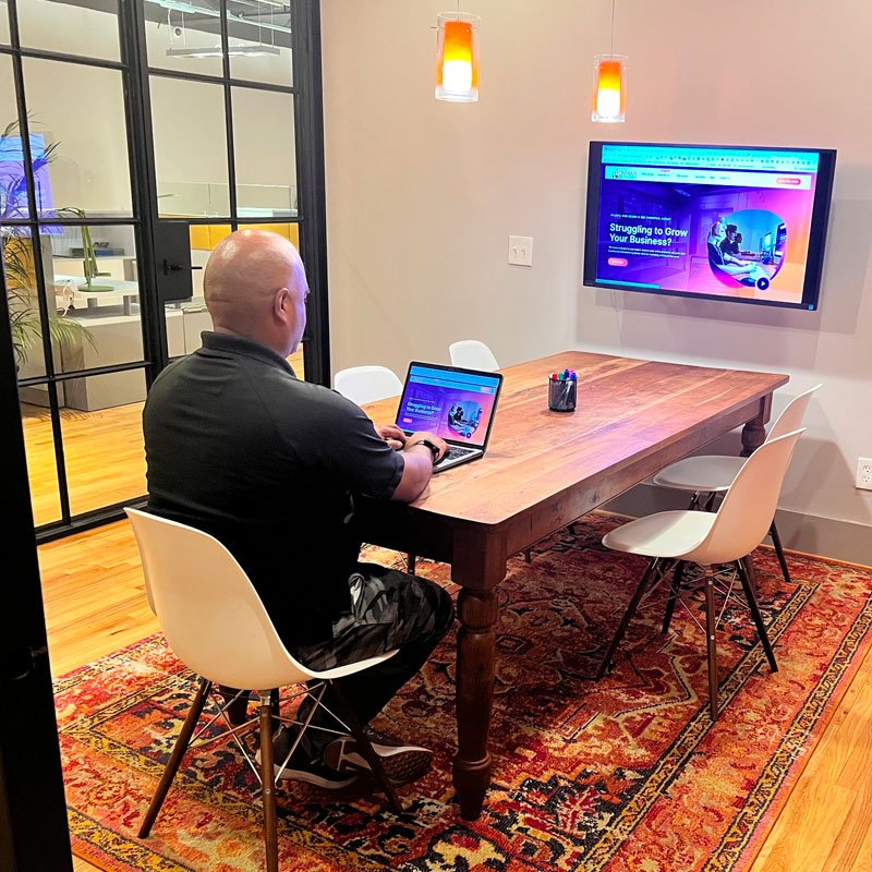 A man reviewing shows on TV while sitting at a table with a laptop.