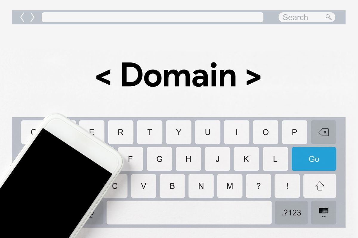 A cell phone next to a keyboard with the word domain on it, providing guidance on increasing domain authority.