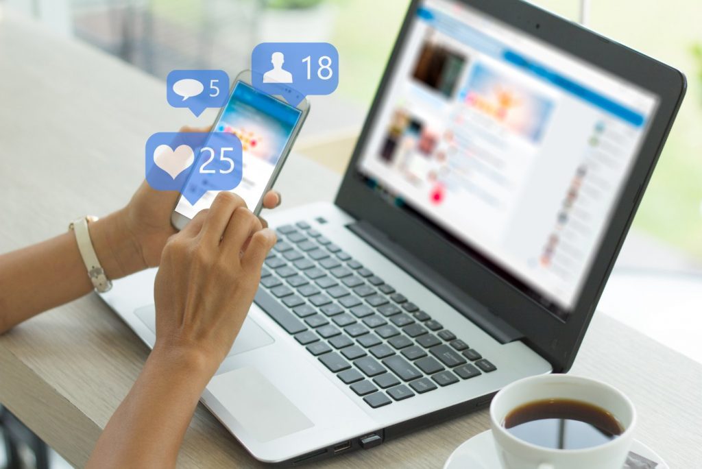 A woman utilizing marketing channels through a laptop displaying social media icons.