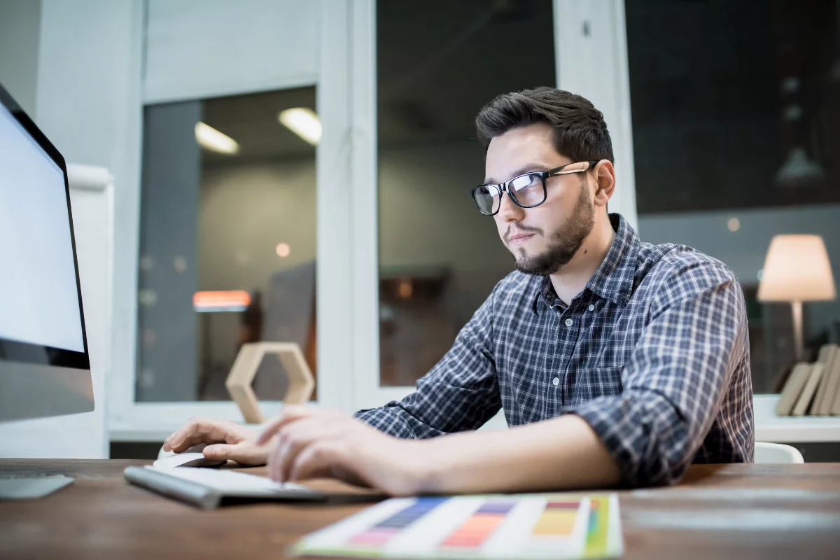 The Advantages Of Hiring Professional WordPress Web Designers Near You 4 A man sitting at a desk using a computer for WordPress web designing.