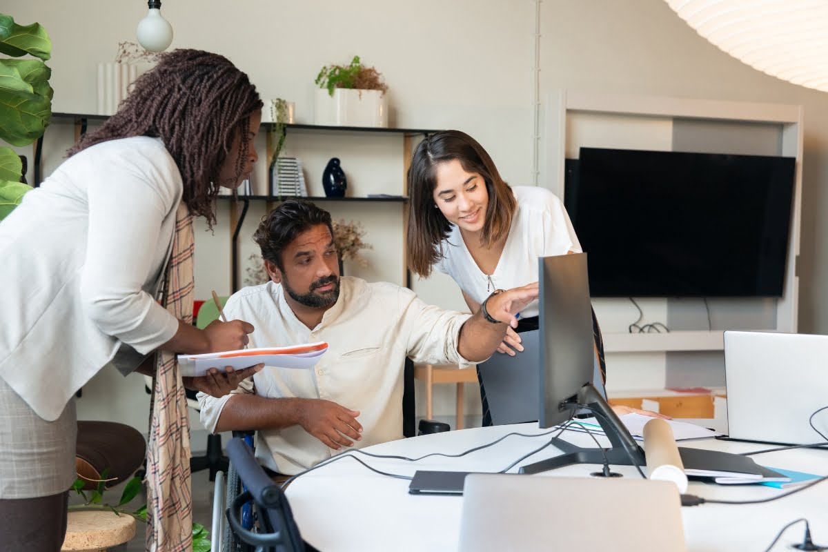 Your Guide to Choosing the Perfect Home Improvement Marketing Agency 5 Three people in a marketing agency office looking at a computer screen.
