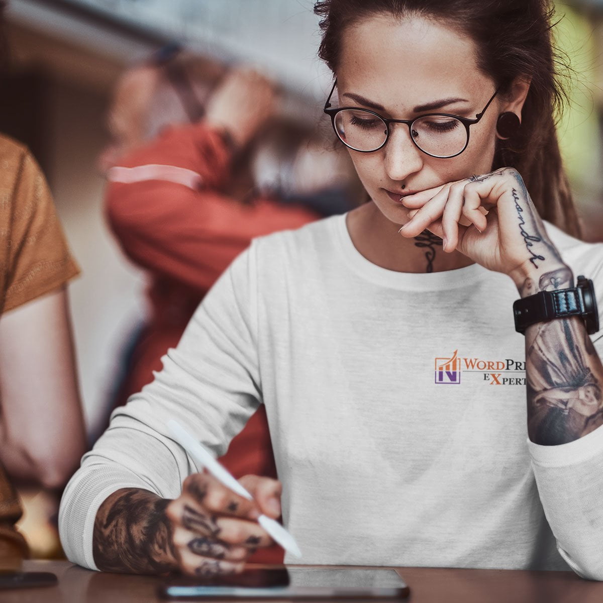 A woman offering wordpress services with tattoos sitting at a table.