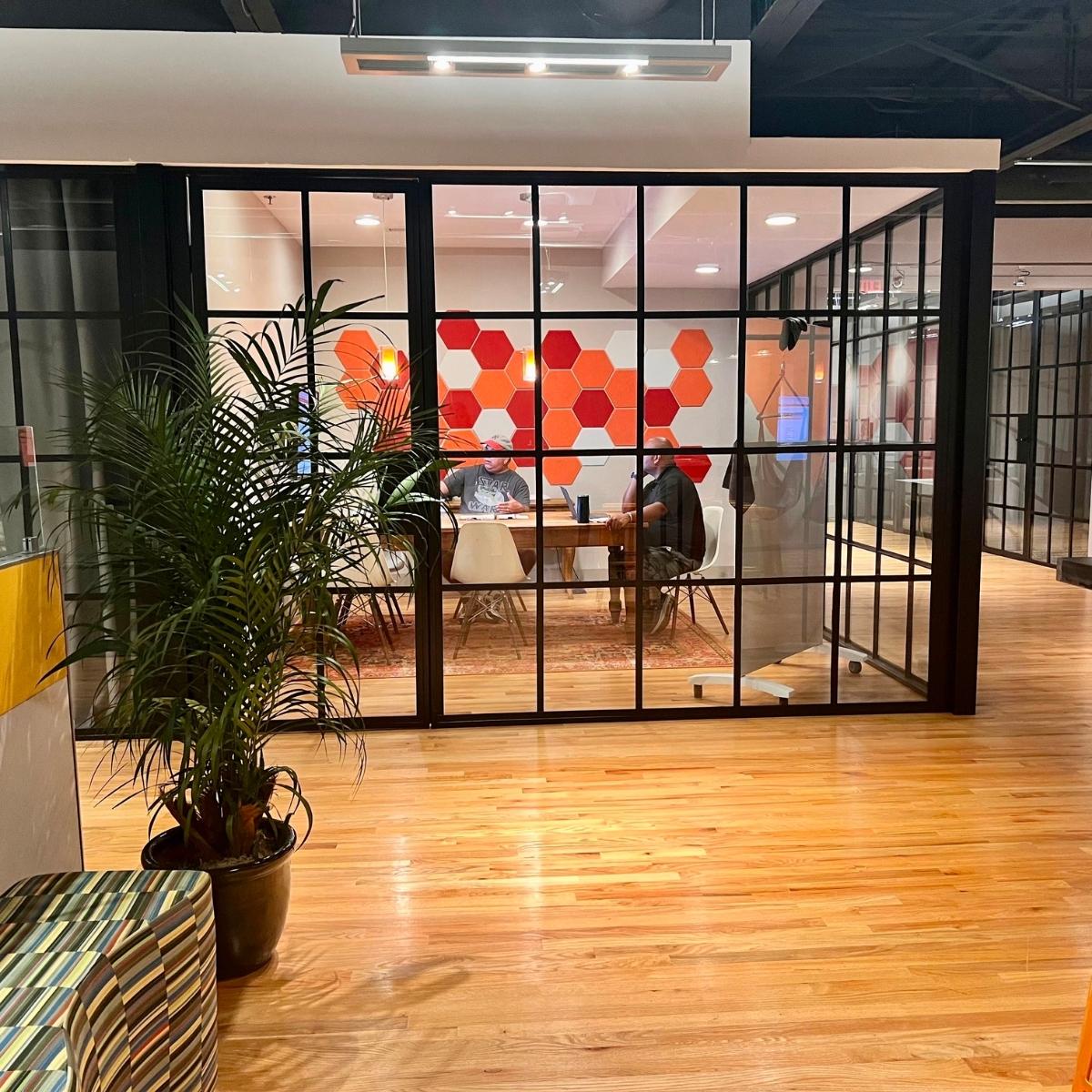 An office with a glass wall and a wooden floor, ideal for a Roswell marketing agency.