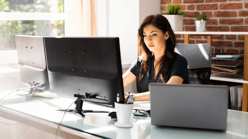 Construction Marketing Strategies: Your Roadmap to Brand Success 6 A woman brainstorming content ideas at her desk with two computers.