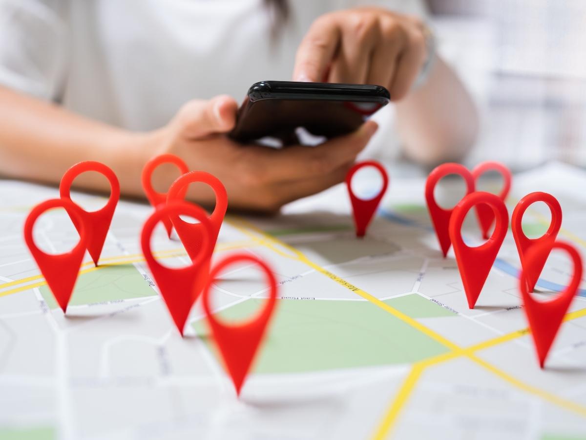 SEO Geo-Targeting: Your Roadmap to Success 2 A person using a cell phone to search for local businesses with red pins on a map trying to master local seo and geo-targeting strategies.