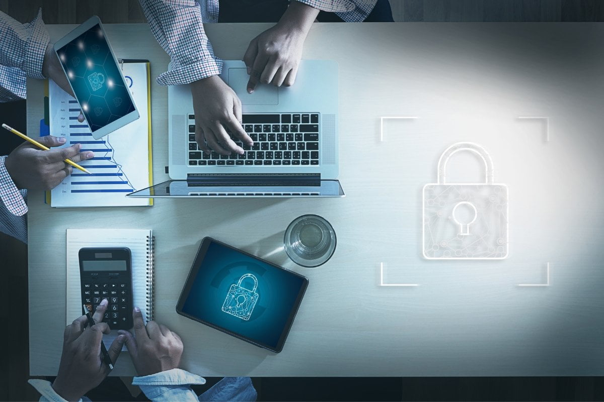 A group of people working at a desk with laptops secured by padlocks for increased internet security.