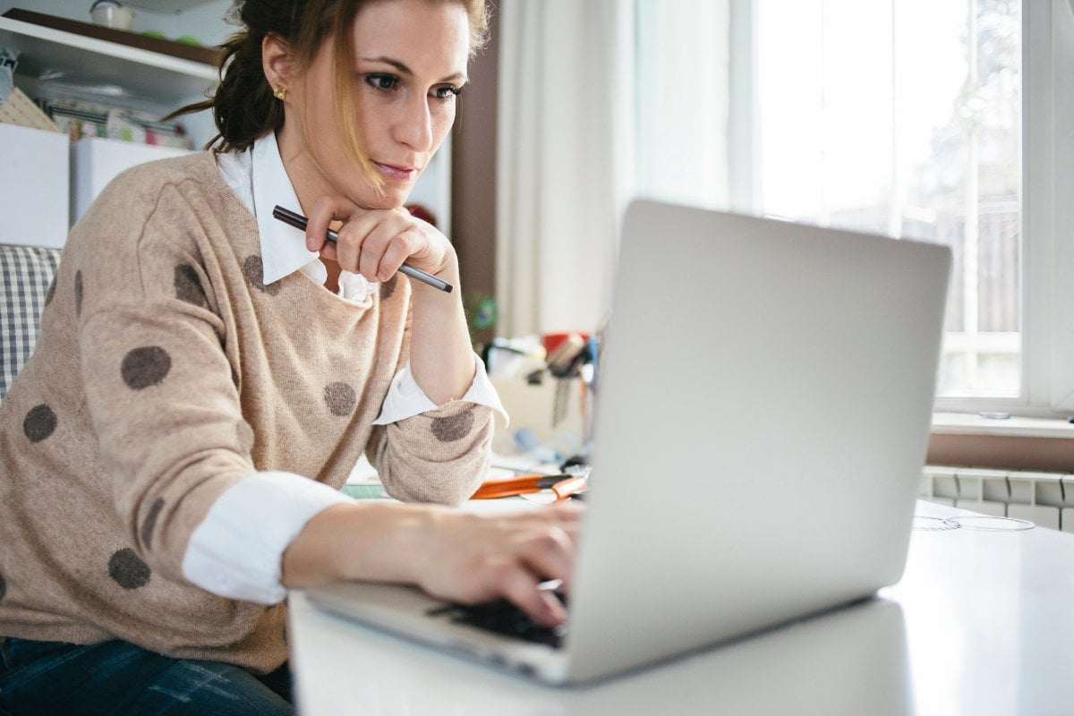 A woman optimizing her Google My Business profile at a desk with a laptop.