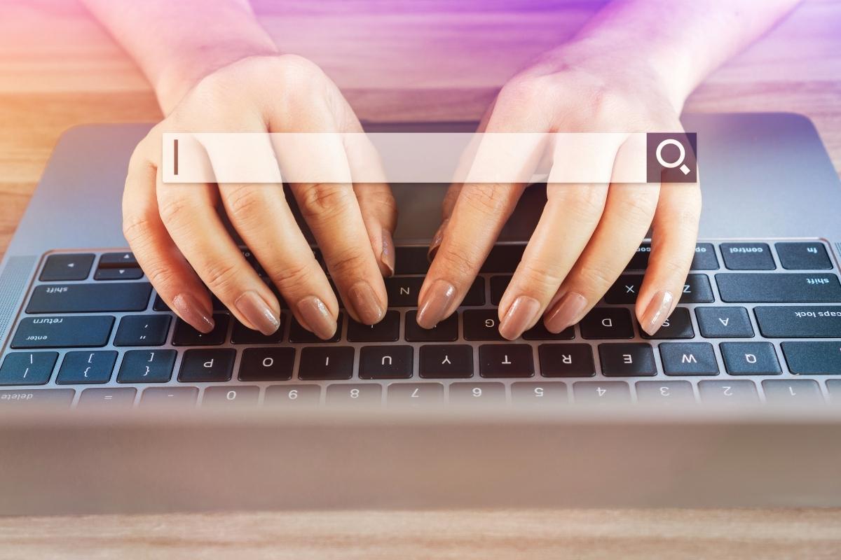A woman efficiently typing on a laptop while using a search bar to navigate a website.