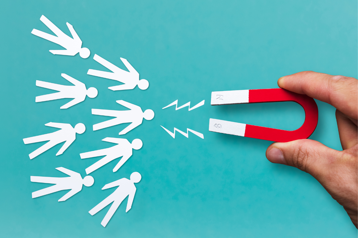 Lead Magnet Ideas: Creativity To Skyrocket Your Email Subscribers 3 A hand holding a magnet to a group of paper people.