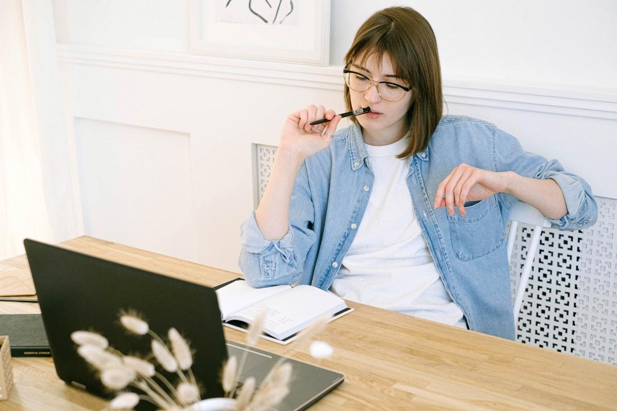 A young woman writing blog posts at a desk with a laptop.