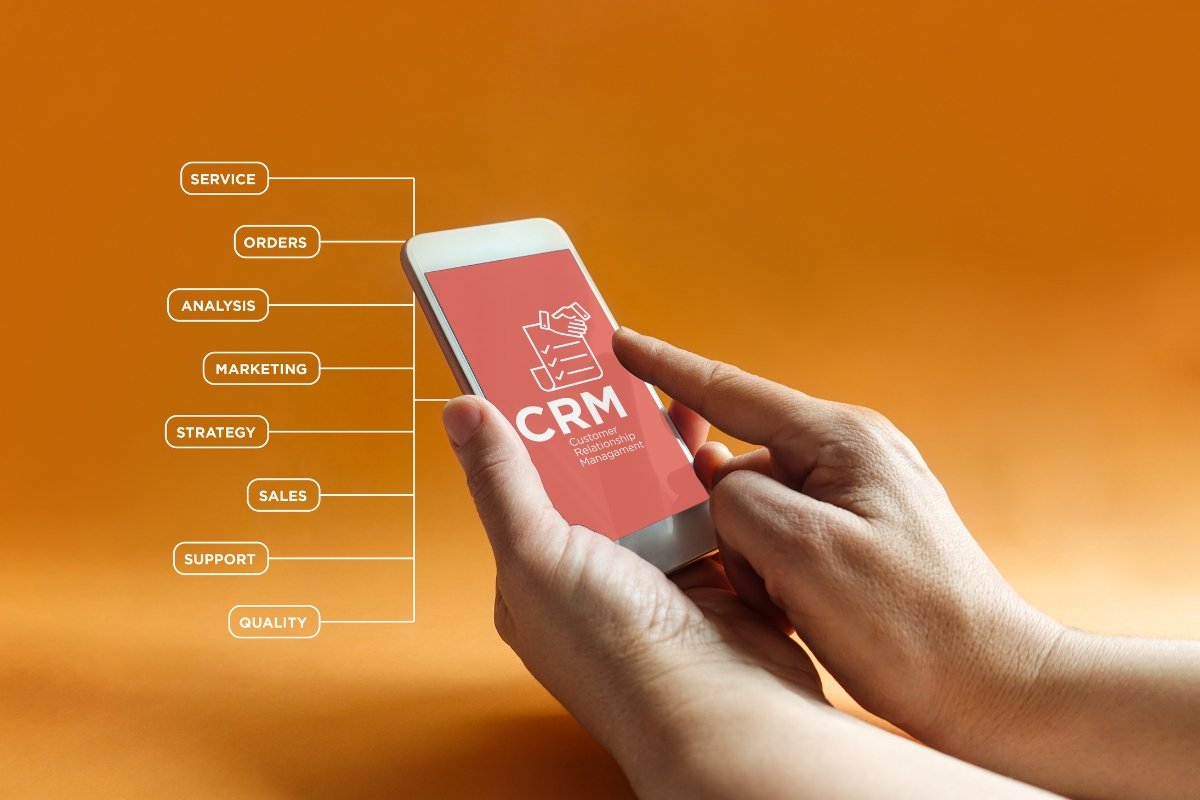A smartphone displaying the word "CRM" being held in a hand.