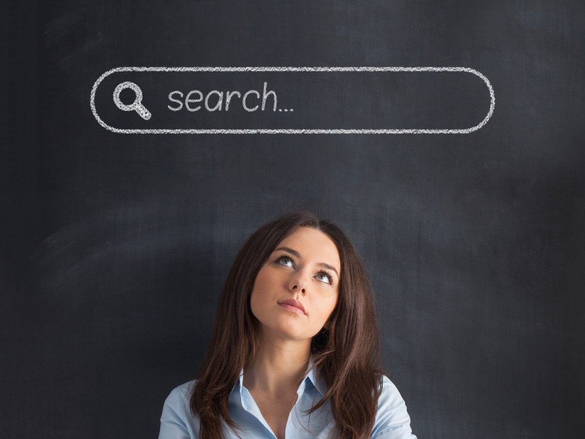 A woman examining a blackboard with a website search bar sketched on it.