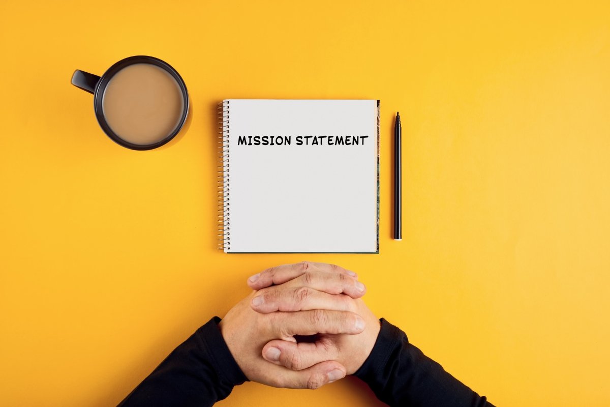 A person holding a notebook with information on how to write a mission statement.