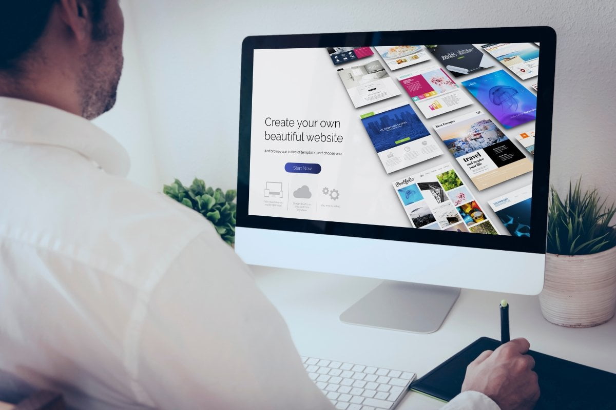 A man is using website design software to view a computer screen filled with images.