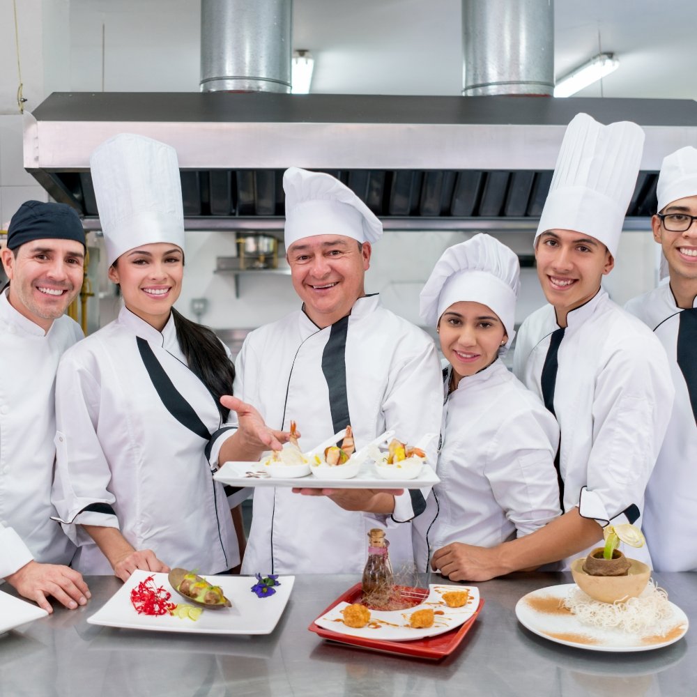 A team of chefs posing for a promotional photo in a restaurant for a catering marketing agency.