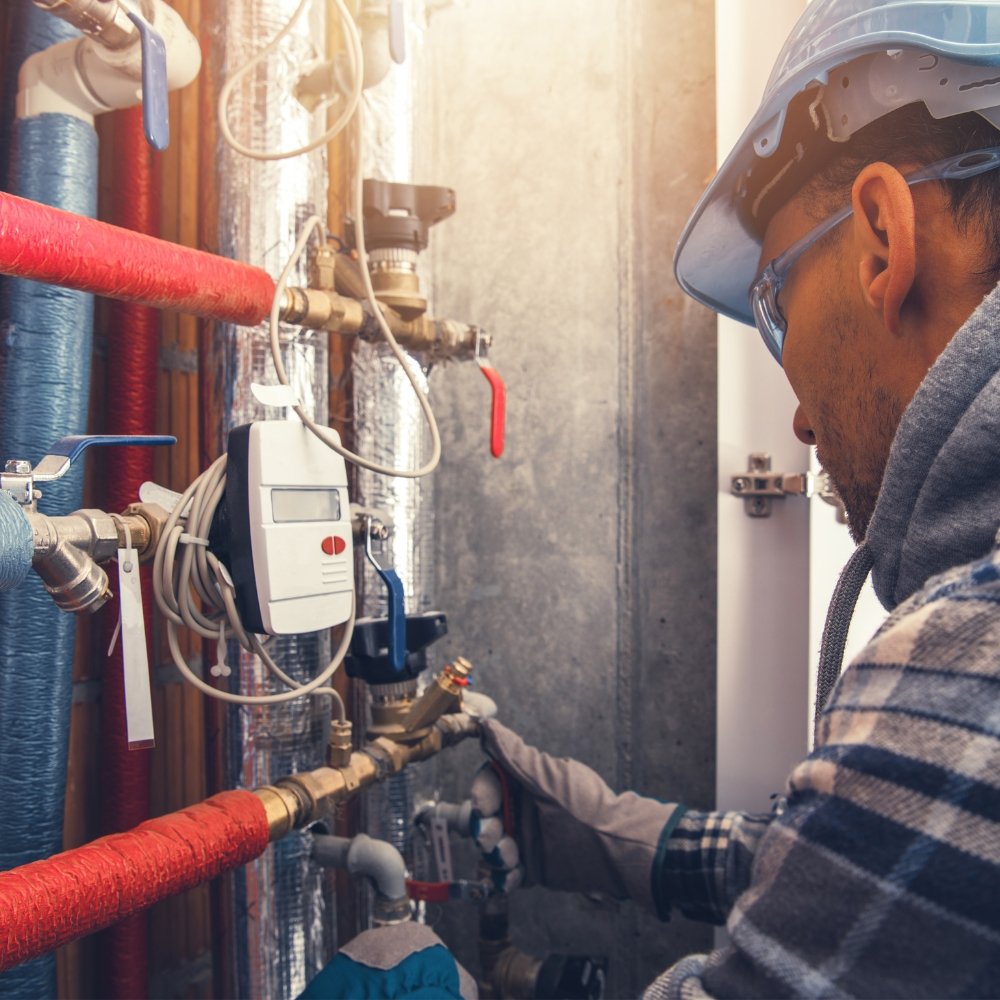 A man in a hard hat is working on an HVAC pipe.