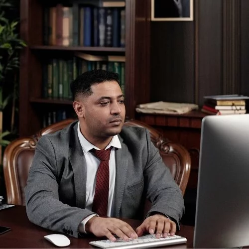 A man in a suit at a law firm desk using a computer for digital marketing.