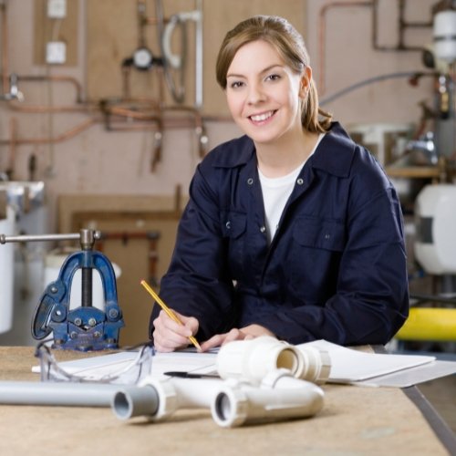 A female plumber showcasing her skills with pipes and tools as part of plumber marketing services.