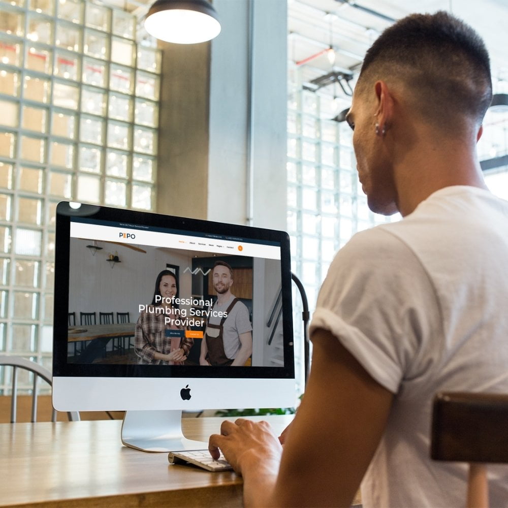 A man at a desk designing a plumber's website.