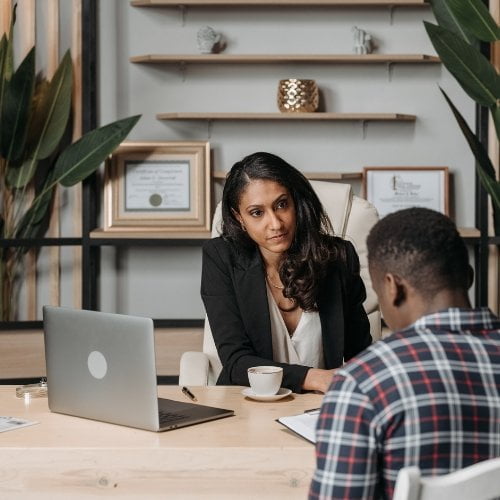 A woman is discussing attorney website design with a man at a desk in an office.