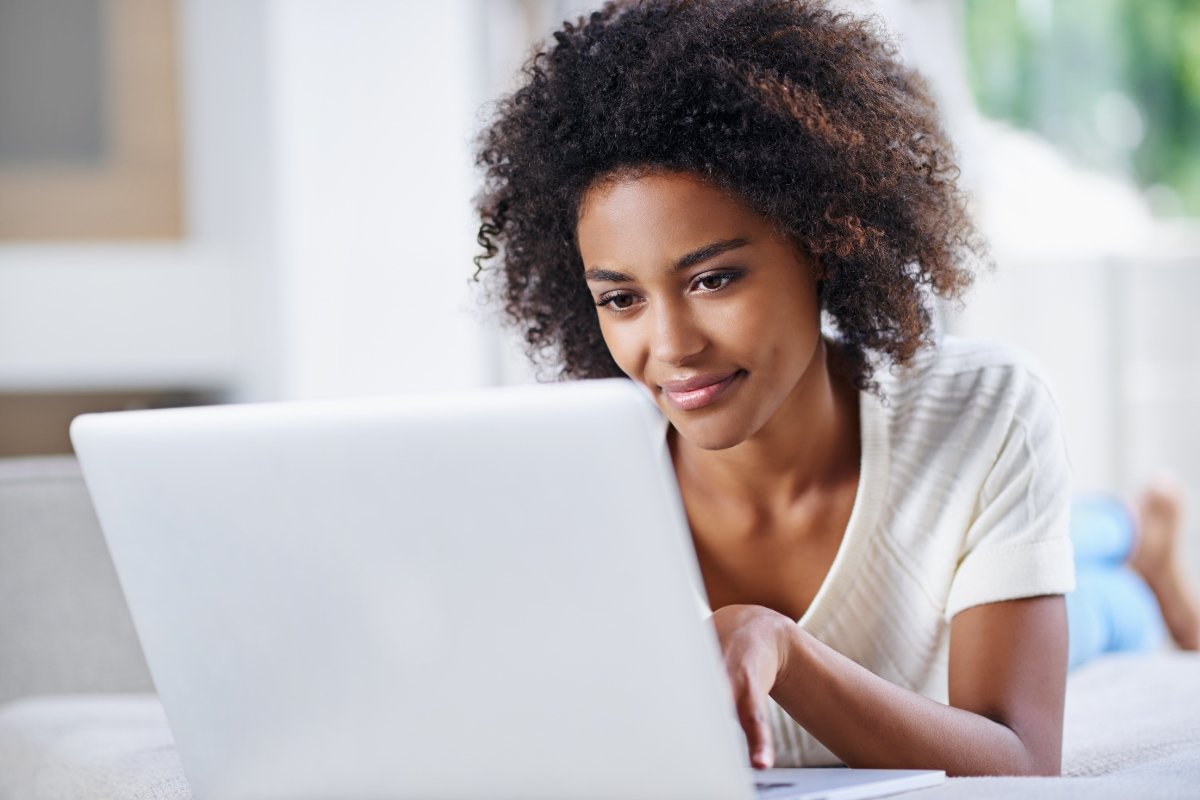 A young African American woman using a laptop at home while performing website maintenance.