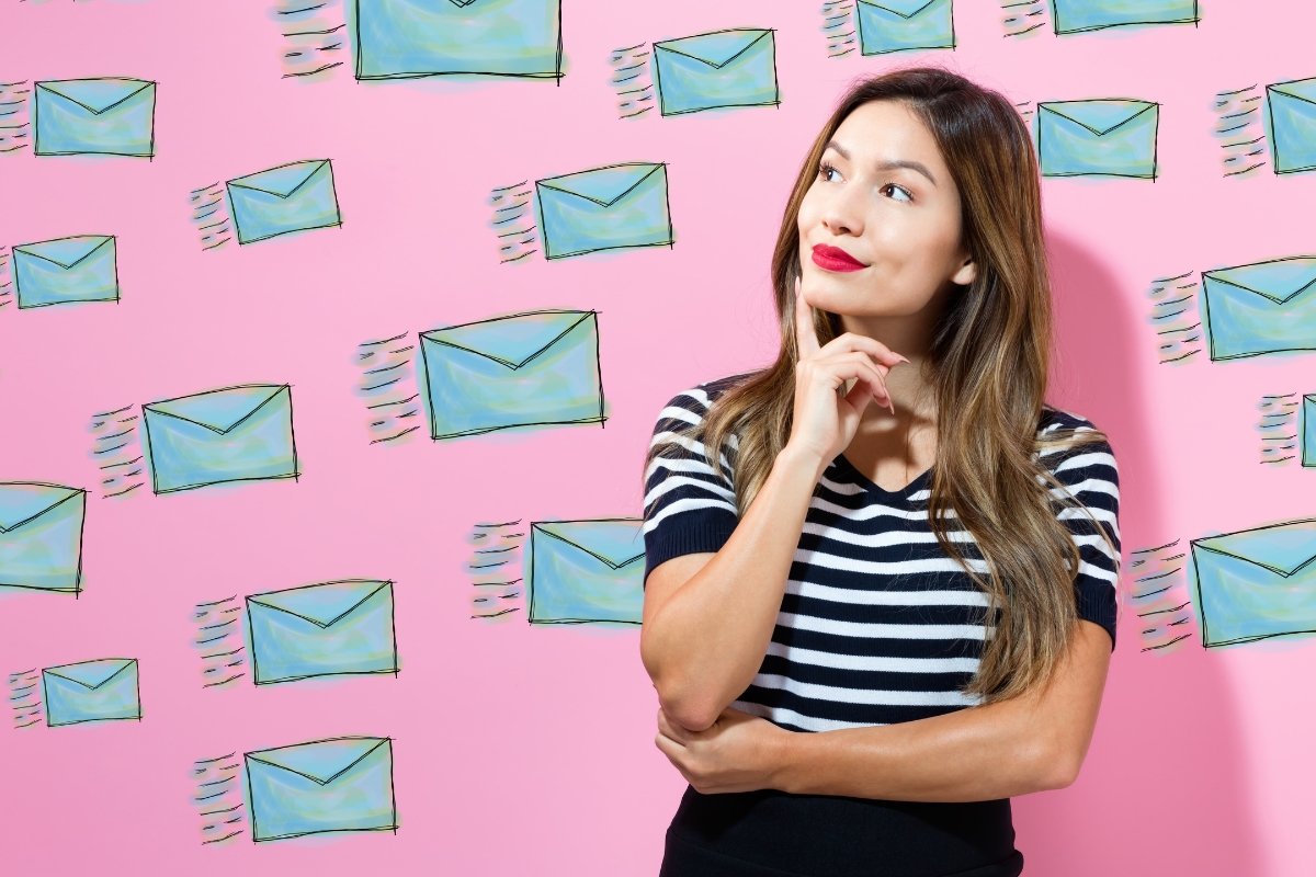 A woman utilizing Google Alerts, photographed in front of a pink wall adorned with envelopes.