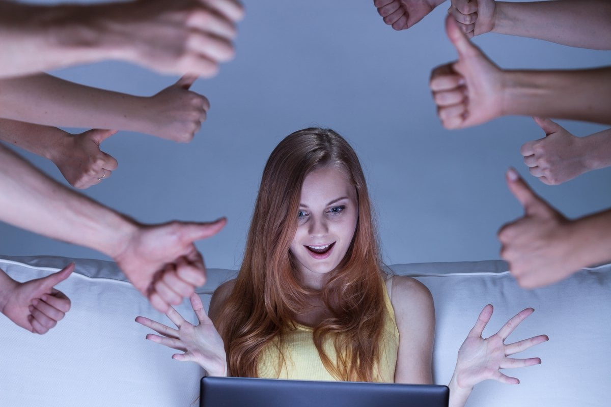 A woman giving thumbs up on a couch while using Facebook debugger.