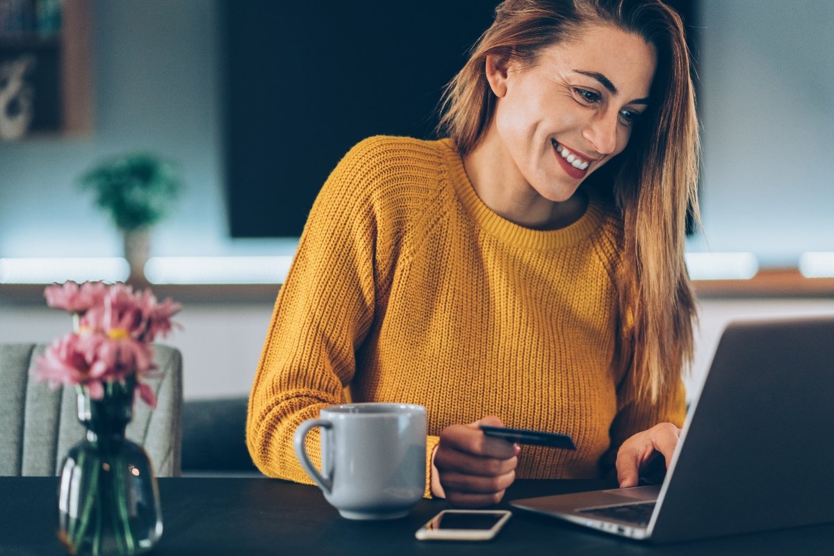 A woman multitasking with automated booking while using a laptop and sipping coffee.