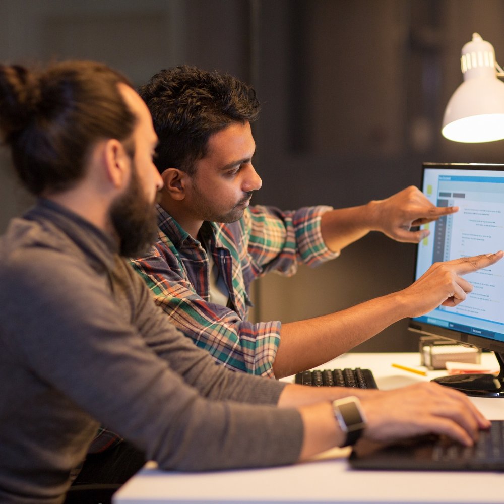 Two men analyzing Woocommerce SEO services and strategies on a computer screen.