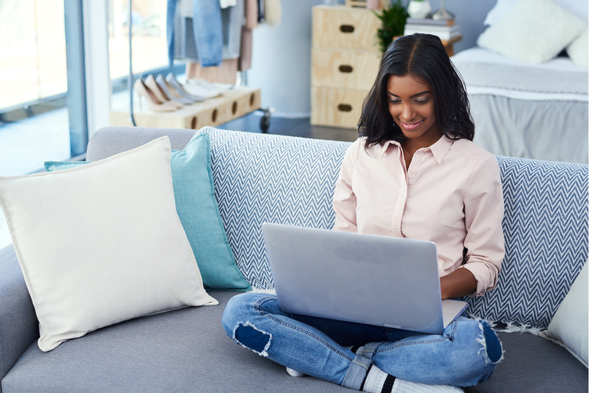Apple Business Connect And Profile Optimization 2 A businesswoman boosting her online presence with her laptop while sitting on a couch.