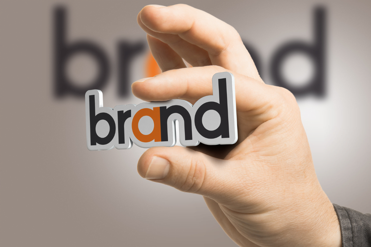 10 Game-Changing Strategies To Skyrocket Your eCommerce Business Success 2 A man is holding up a piece of paper with the word "brand" on it, representing an ecommerce business.