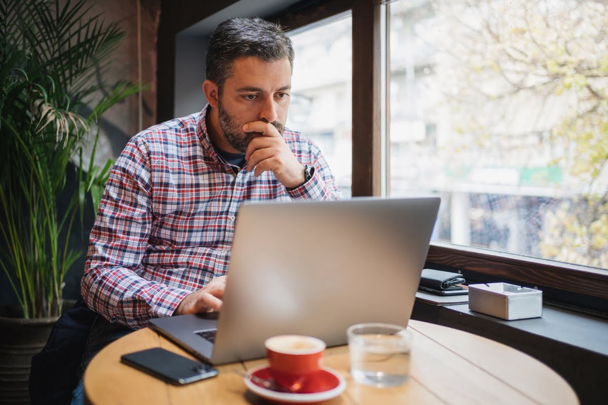 Exploring Website Traffic Sources for Success 2 A man analyzing website traffic sources with a laptop and a cup of coffee on the table.