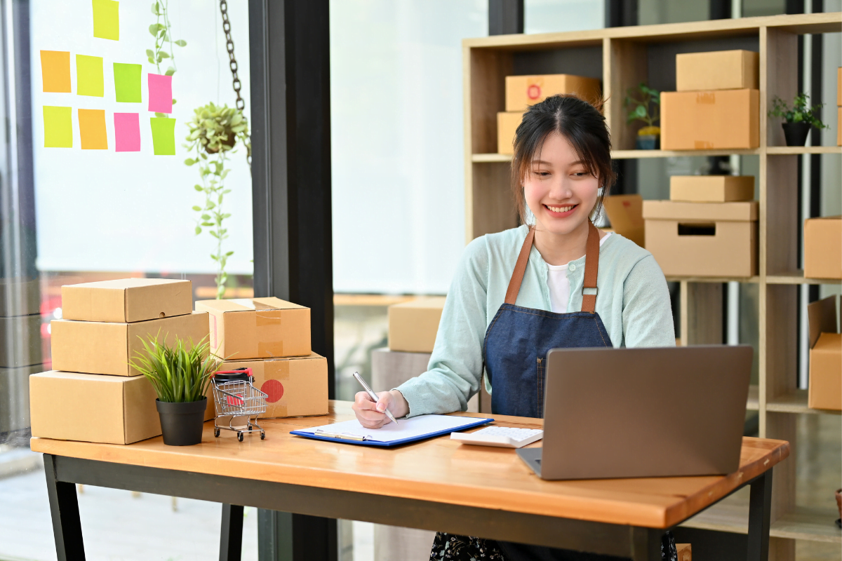 Boost E-Commerce Sales With WooCommerce Gift Cards Plugin 2 A business woman working at a desk with a laptop and boxes.