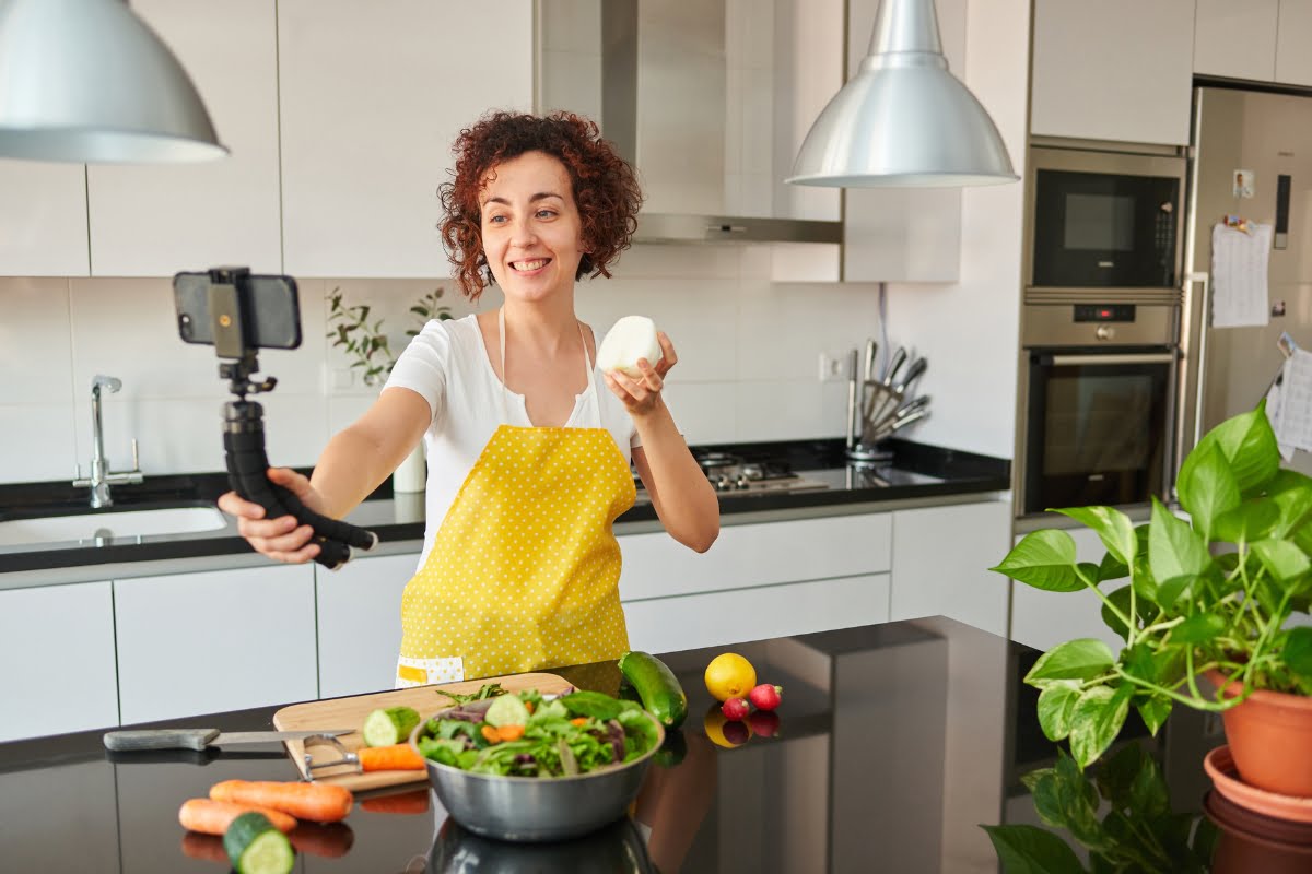 The Power of Influencer Marketing: How to Win Over Your Target Audience 6 A woman in an apron is engaging in influencer marketing by taking a selfie in the kitchen.