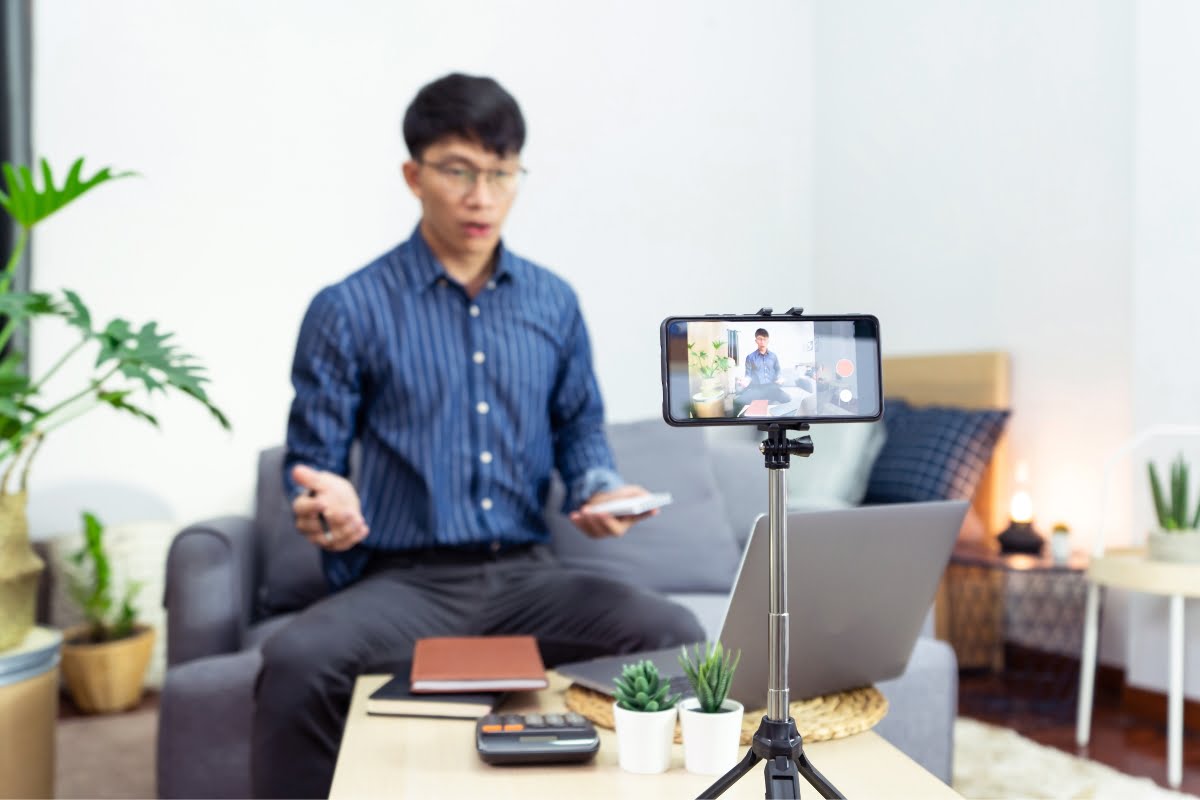 The Power of Influencer Marketing: How to Win Over Your Target Audience 7 An influencer is sitting on a couch and using a phone to take a video call.