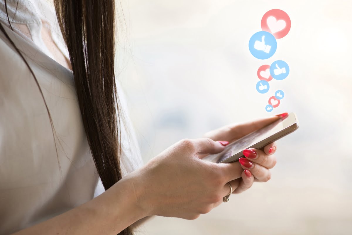 The Pros and Cons of Using Link Shorteners on Social Media 3 A woman holding a cell phone with social icons and link shorteners on it.