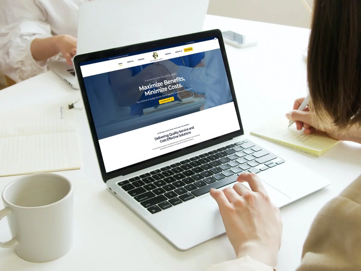 A woman from the Freshour Group is working on a laptop at a desk.