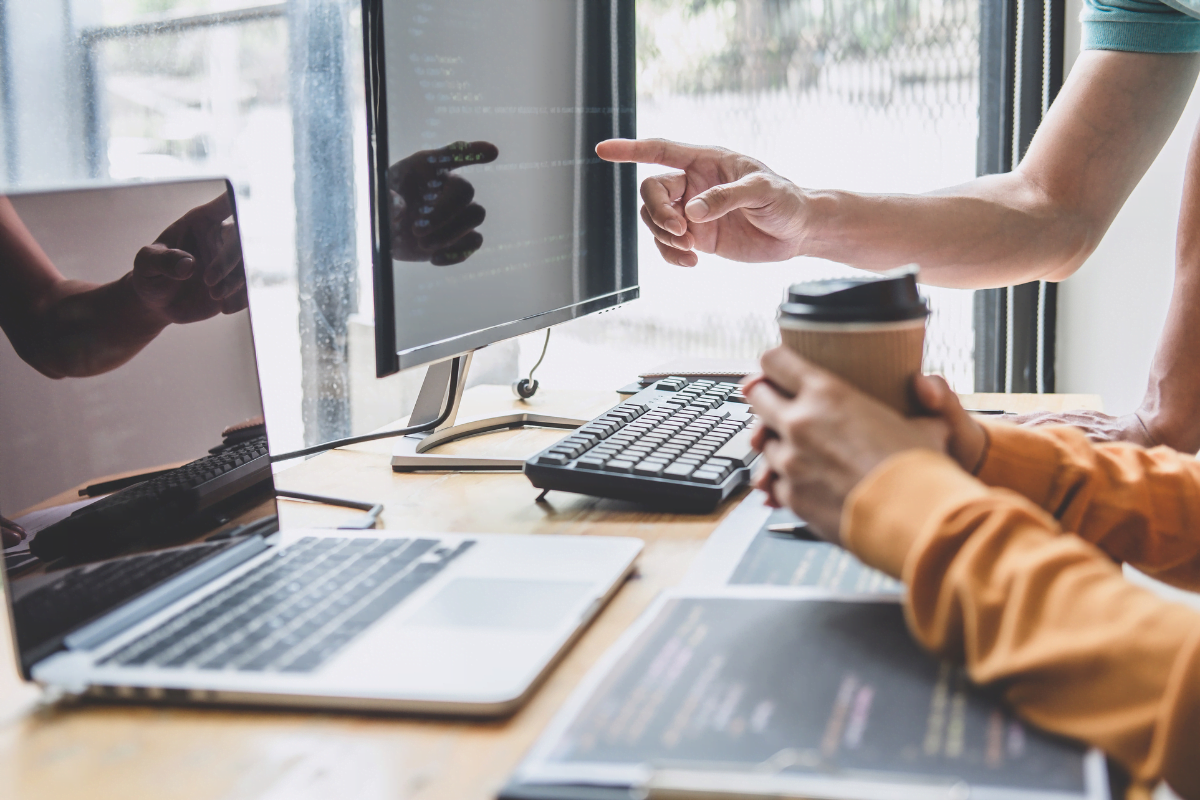 Two people discussing the worth of SEO while pointing at a computer screen.