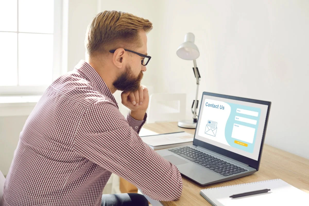 Landing Page Conversions: The Ultimate Guide to Skyrocket Your Sales 3 A man sitting at a desk, focused on his laptop screen for improved landing page conversions.