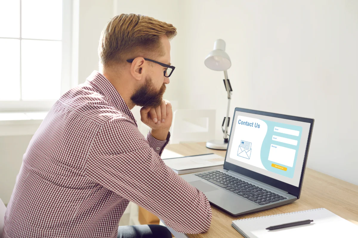 Landing Pages That Convert: The Power Of High-Converting Design 4 A man sitting at a desk, analyzing a laptop screen while optimizing landing pages for maximum conversion rates.