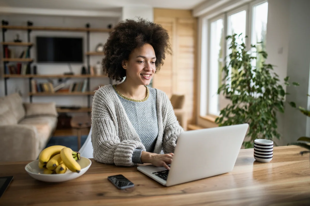 Landing Pages That Convert: The Power Of High-Converting Design 3 A woman sitting at a table with a laptop and bananas nearby.