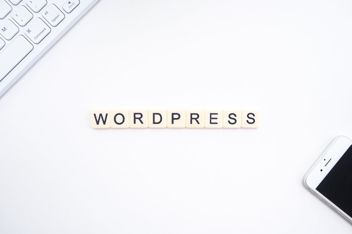 The word wordpress is spelled out on a desk next to a phone and keyboard. This showcases the popular CMS platform.