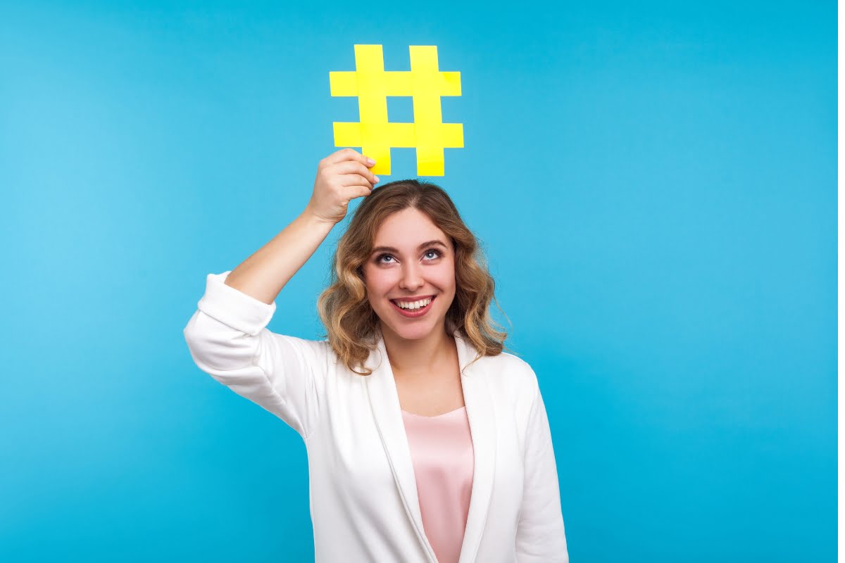 A woman showcasing trendy content for social media by confidently holding up a yellow hash sign on her head.