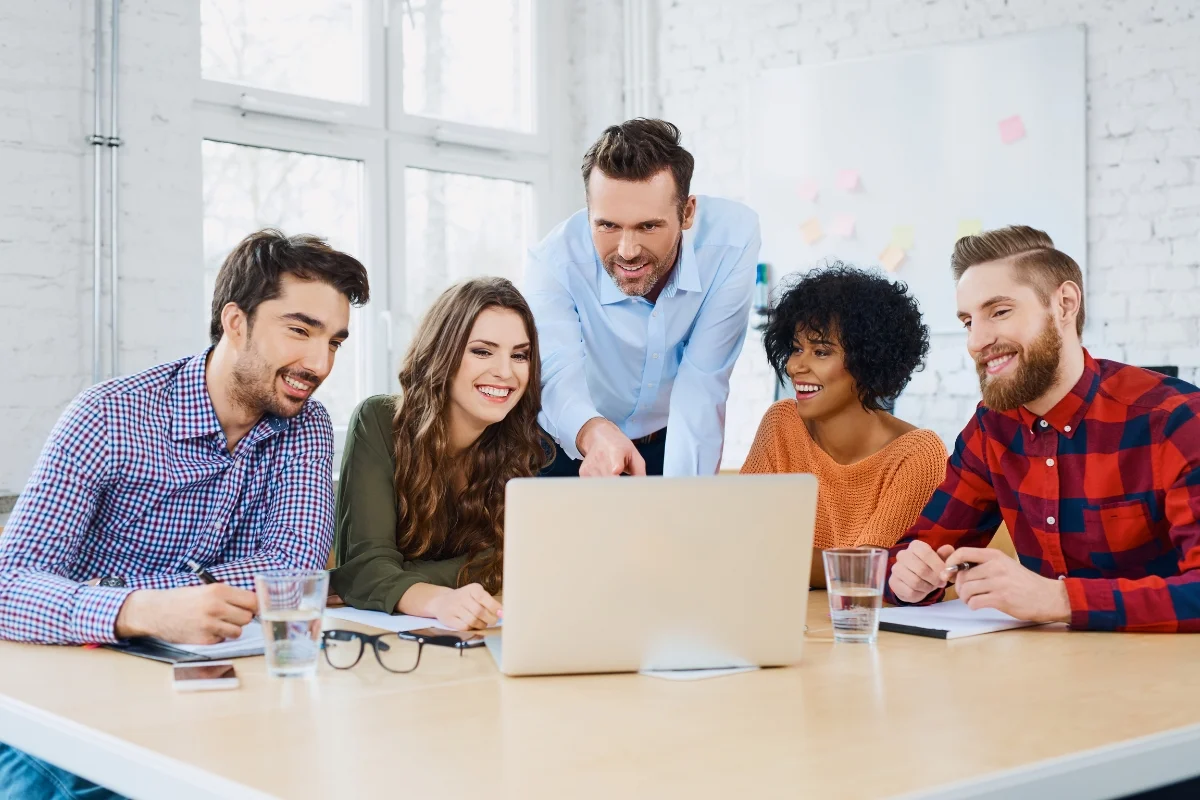 How to Choose the Best Local SEO Company: Expert Tips & Tricks 5 A group of people sitting around a table looking at the best local seo company on a laptop.