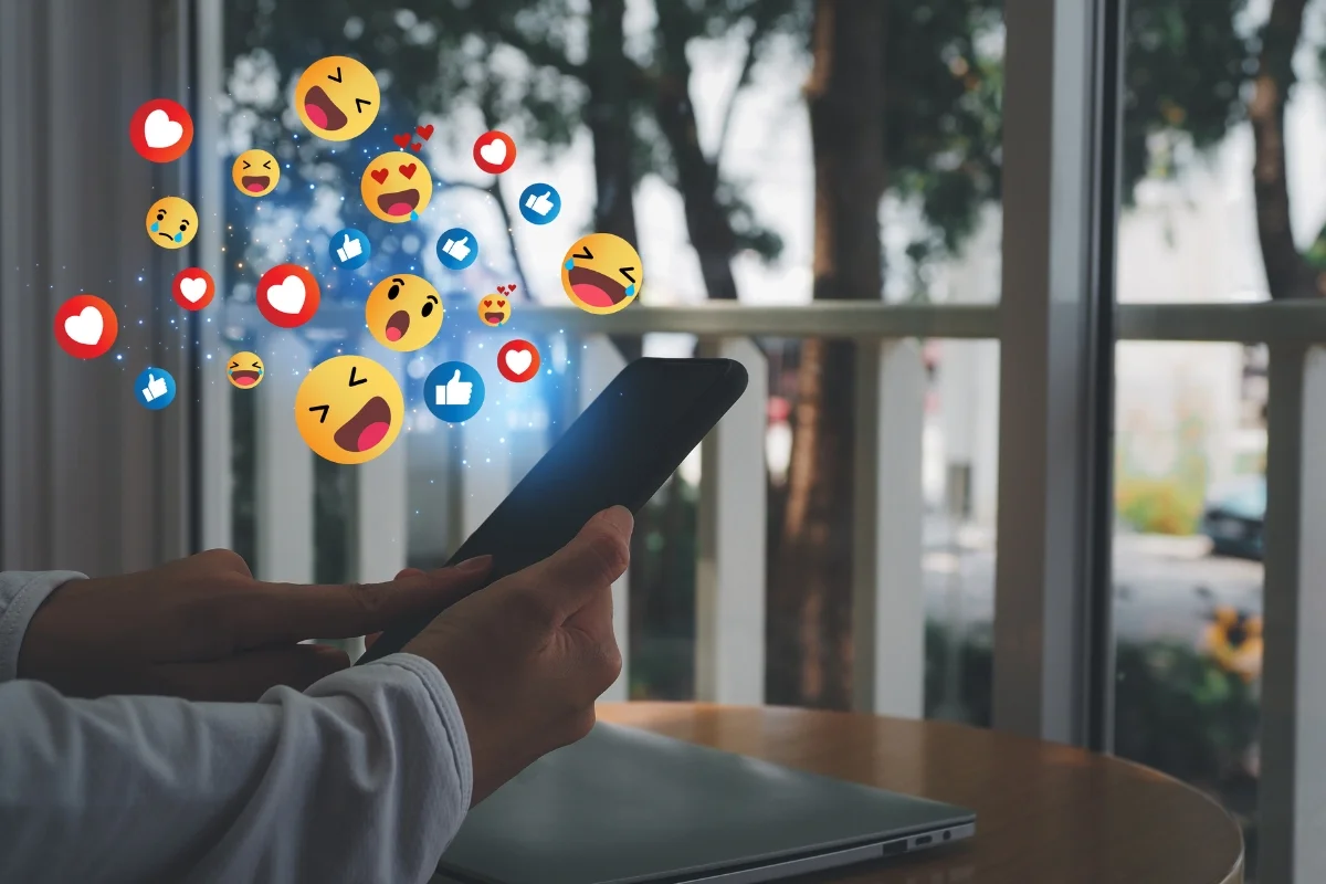 Social Media Copy: Master the Art of Writing Engaging Online Content 5 a person holding up a smartphone with social media icons coming out of it for social media copy