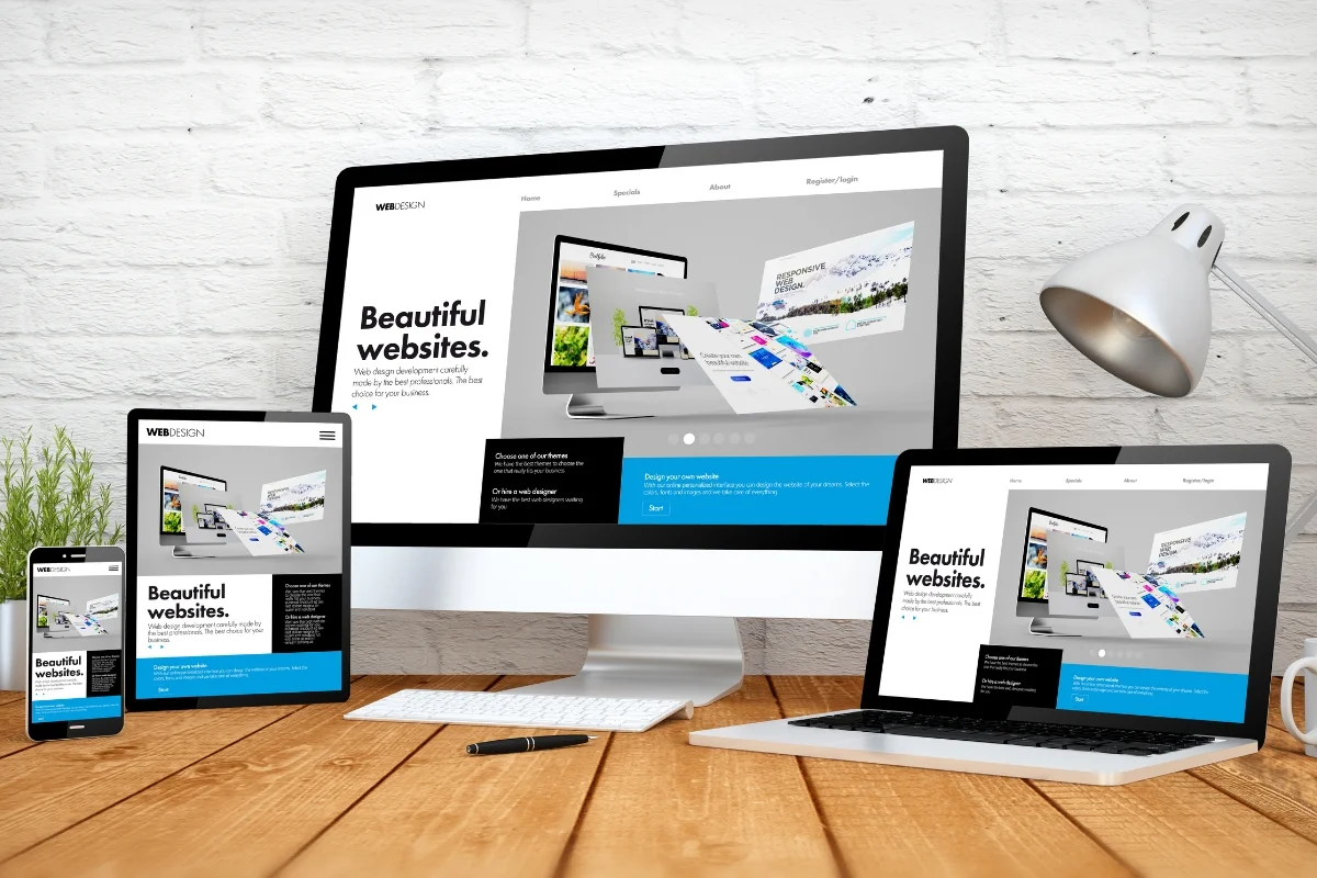 Website Header and Footer: Crafting the Perfect User Experience 2 A laptop, desktop, tablet and phone are displayed on a wooden table as part of the website header and footer.